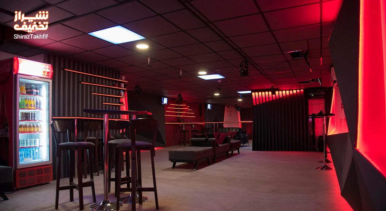 Interior of VR Club featuring red lighting, seating areas, and a drinks refrigerator