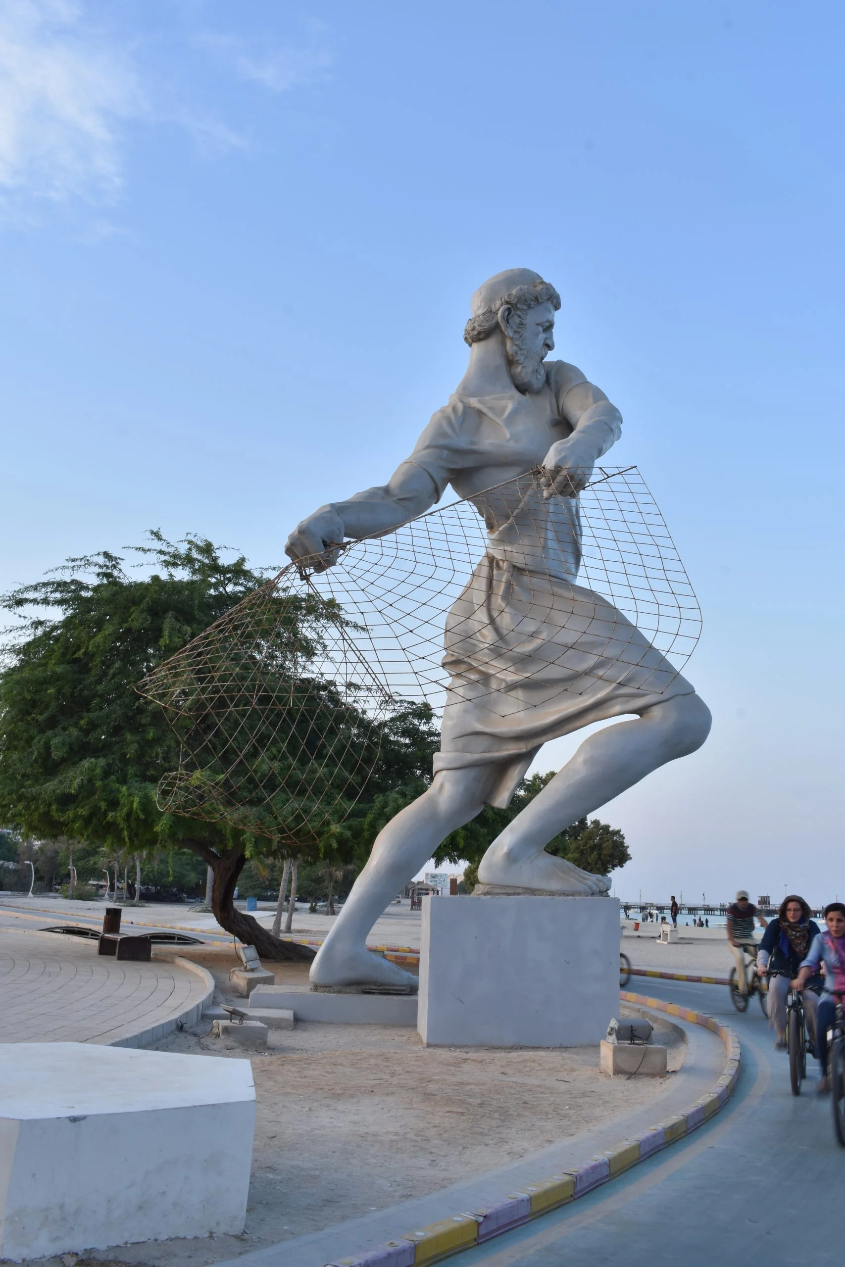 Large outdoor statue of a fisherman casting a net on Kish Island