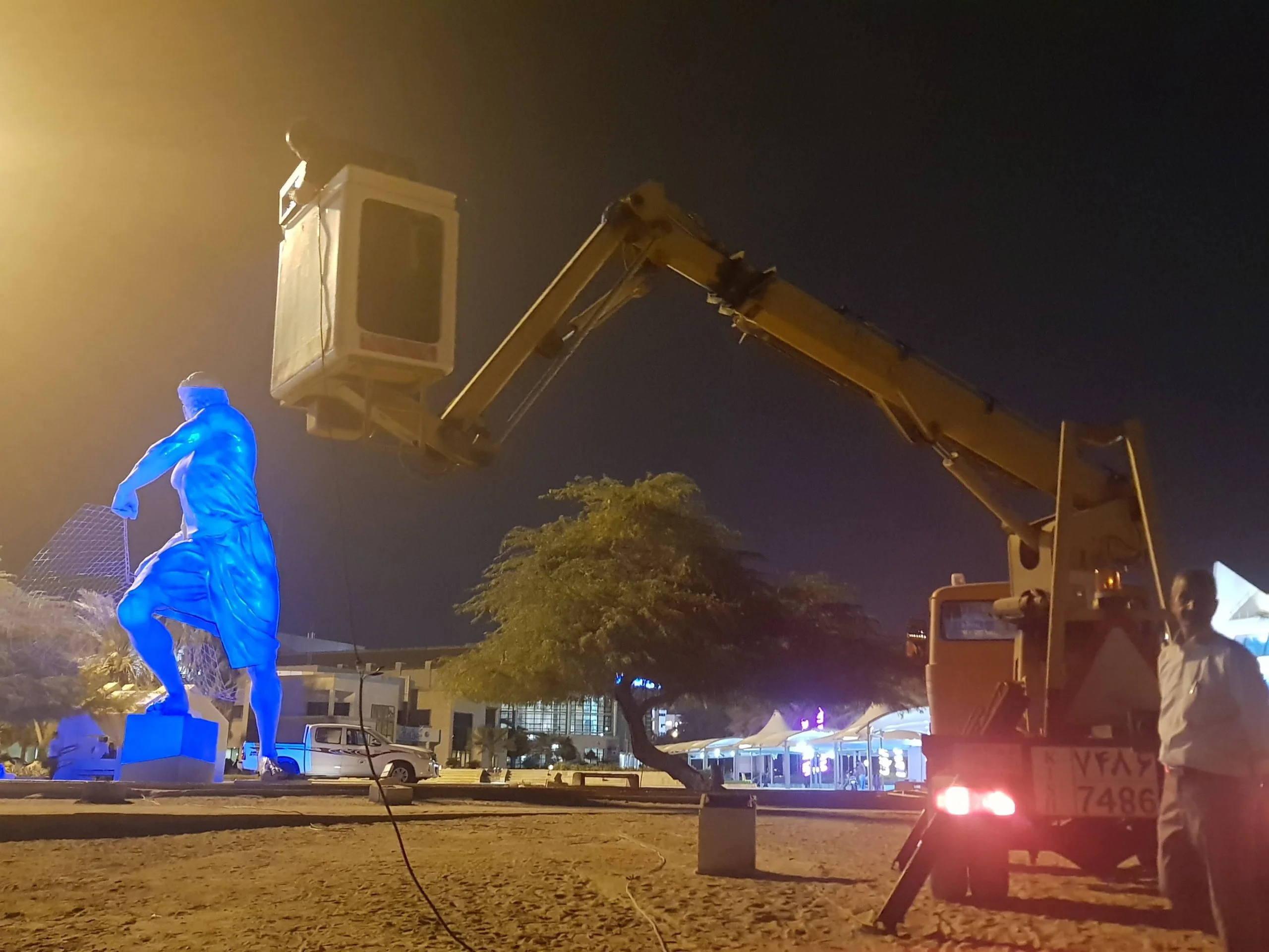 Workers using a crane and cherry picker setup for video mapping on Kish Island